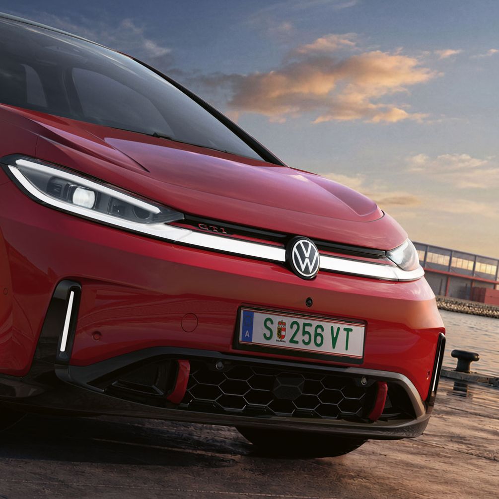 [AI-modified] – Imagem detalhada da parte dianteira de um VW ID.3 GTI vermelho estacionado com os faróis ligados e o logótipo iluminado.