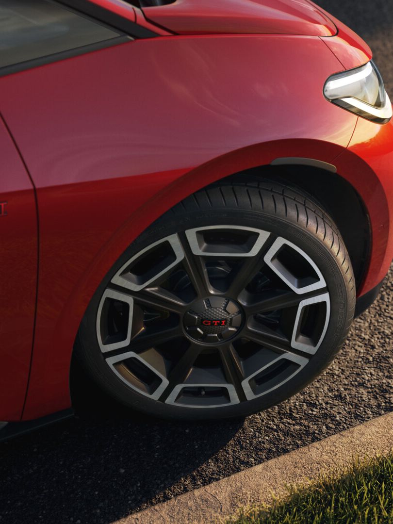 [AI-modified] – Vista frontal de um VW ID.3 GTI vermelho em frente a um edifício com os faróis ligados e o logótipo iluminado.