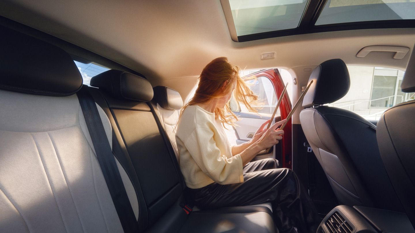 Uma jovem bate alegremente com baquetas no banco do condutor de um VW T-Roc Style.