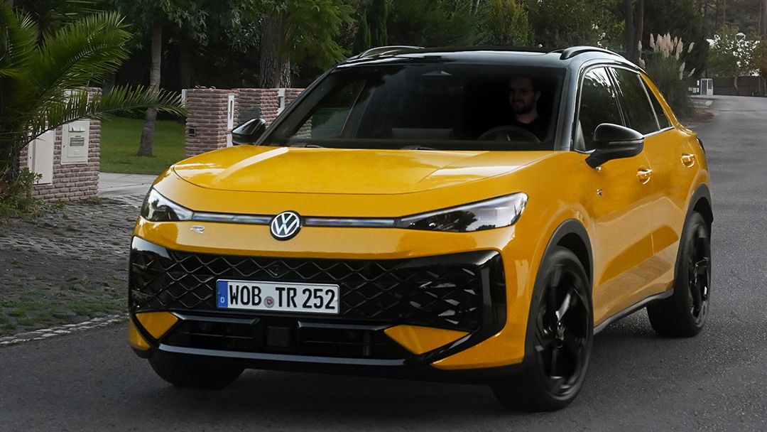 Um VW T-Roc R-Line amarelo percorre uma estrada numa zona arborizada.