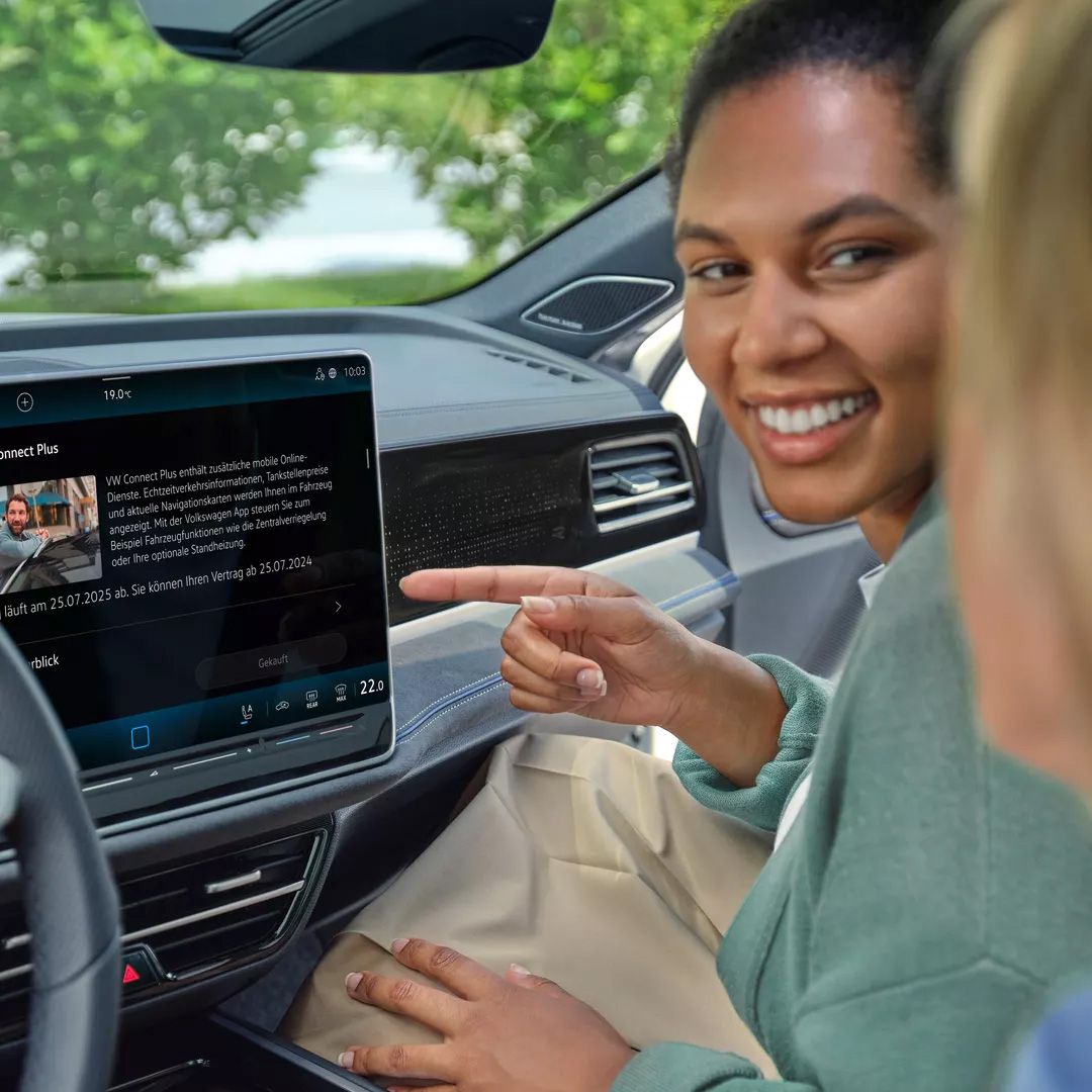 Duas mulheres no interior do automóvel a interagir com o visor do VW Passat.
