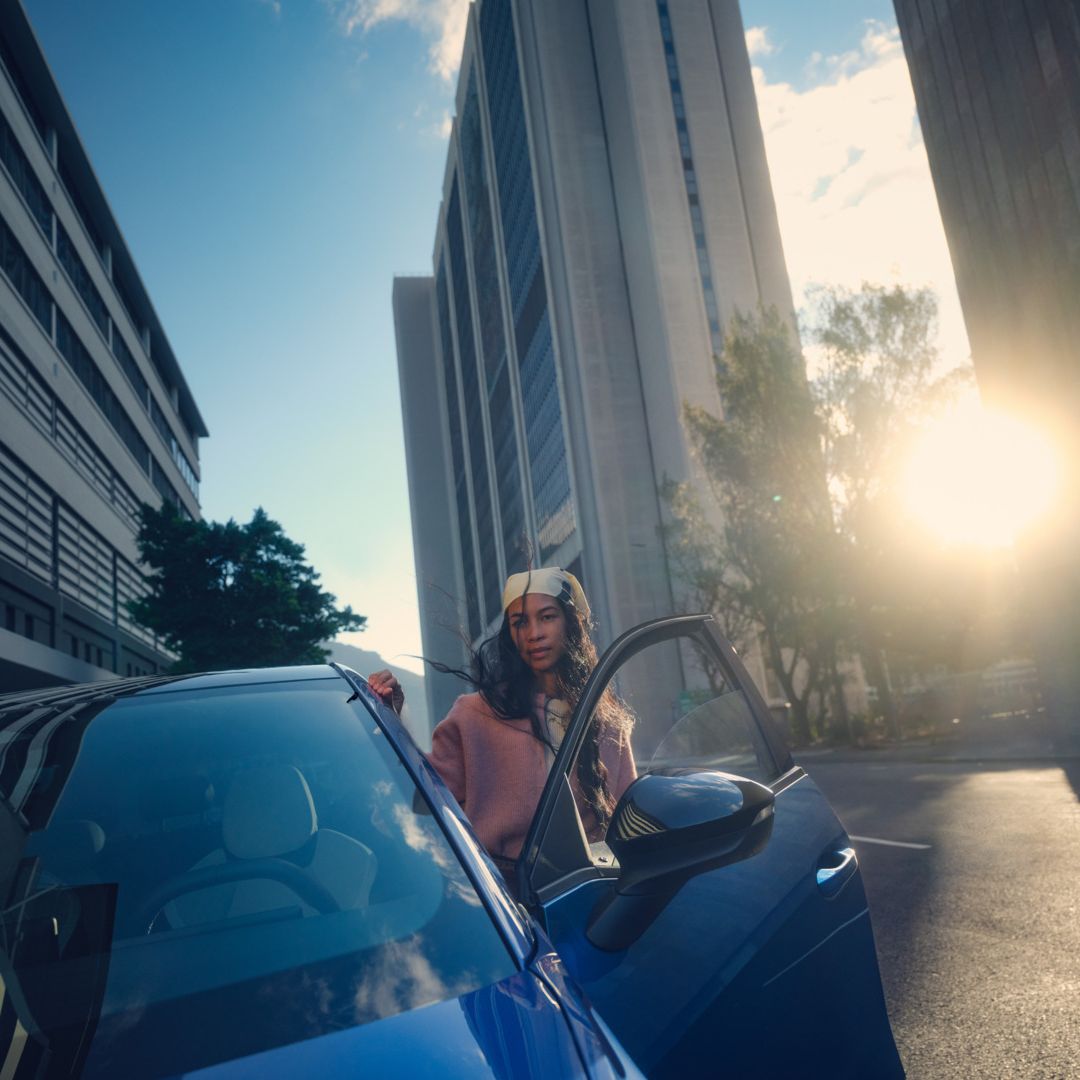 Um VW ID. Polo estacionado numa cidade ao pôr do sol, uma mulher sai do lado do condutor.