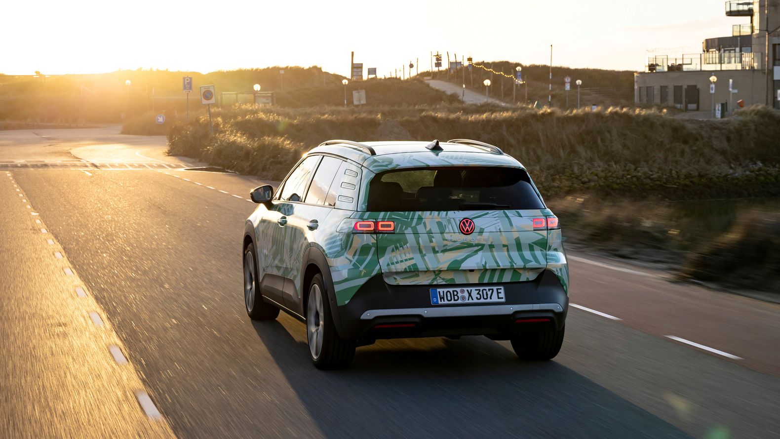 Um VW ID. Cross circula numa estrada rural por uma paisagem montanhosa.