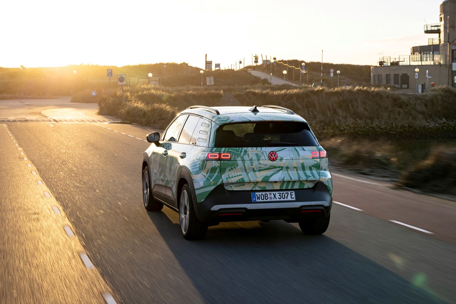 Um VW ID. Cross circula numa estrada rural por uma paisagem montanhosa.