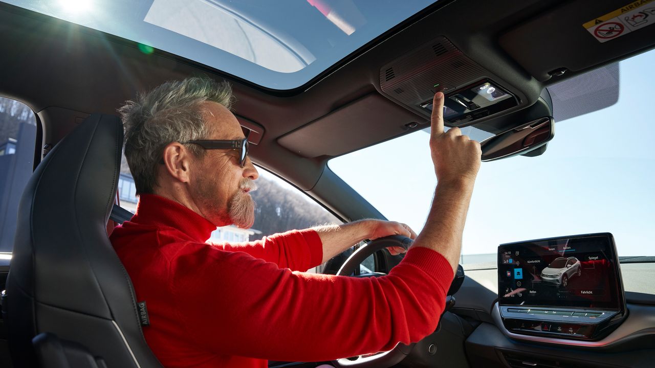 Um homem senta-se num Volkswagen e ativa a chamada de assistência