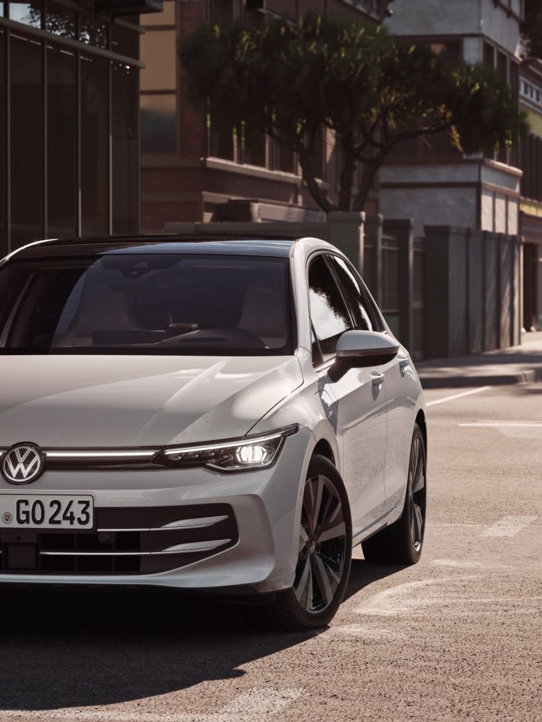 Ein weißer VW Golf von parkt seitlich vor einem Restaurant. Zwei Männer gehen in Richtung des Wagens.