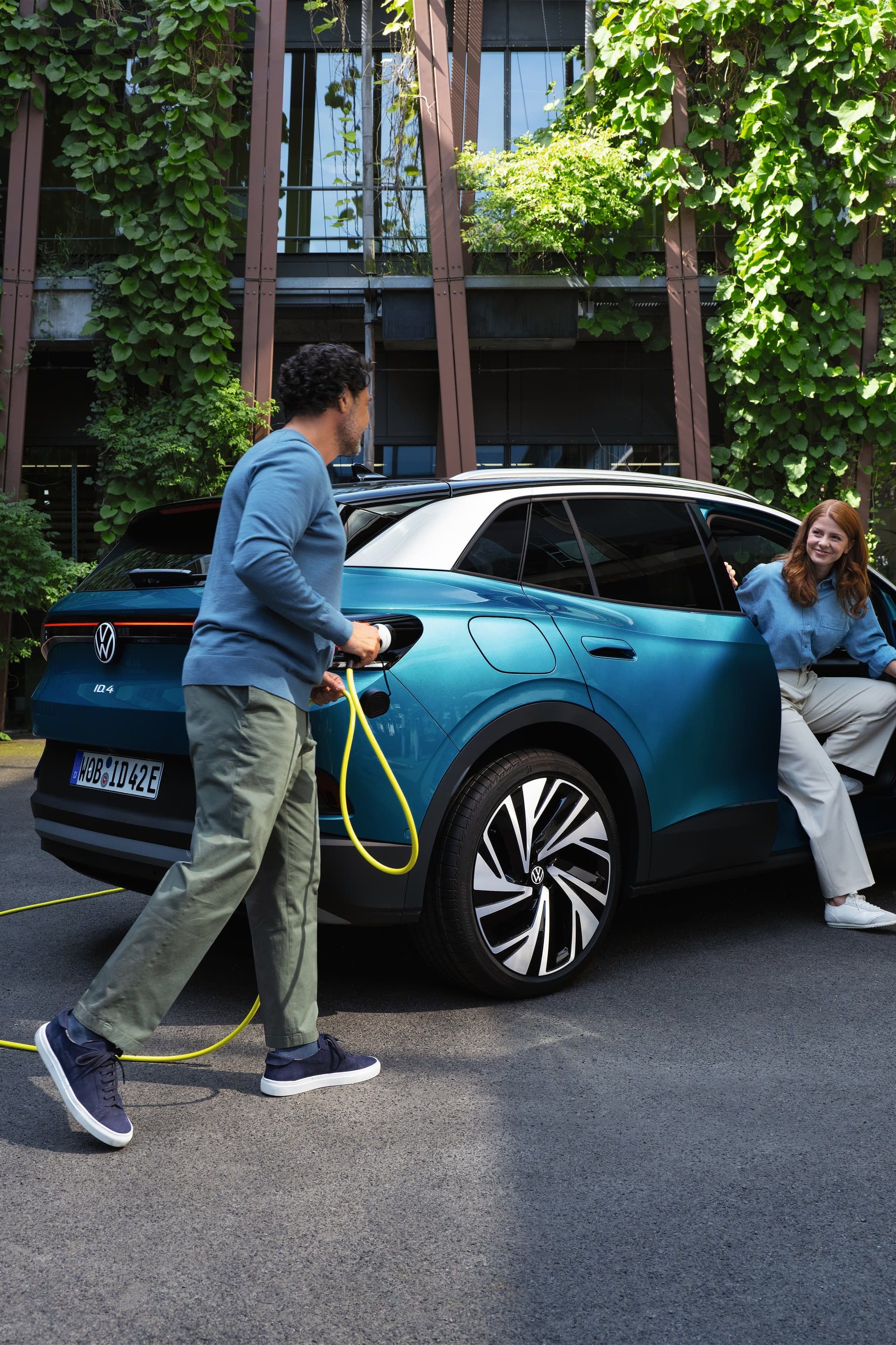 Volkswagen ID4 a carregar e duas pessoas, uma a mexer no carregador e outra a sair do veículo
