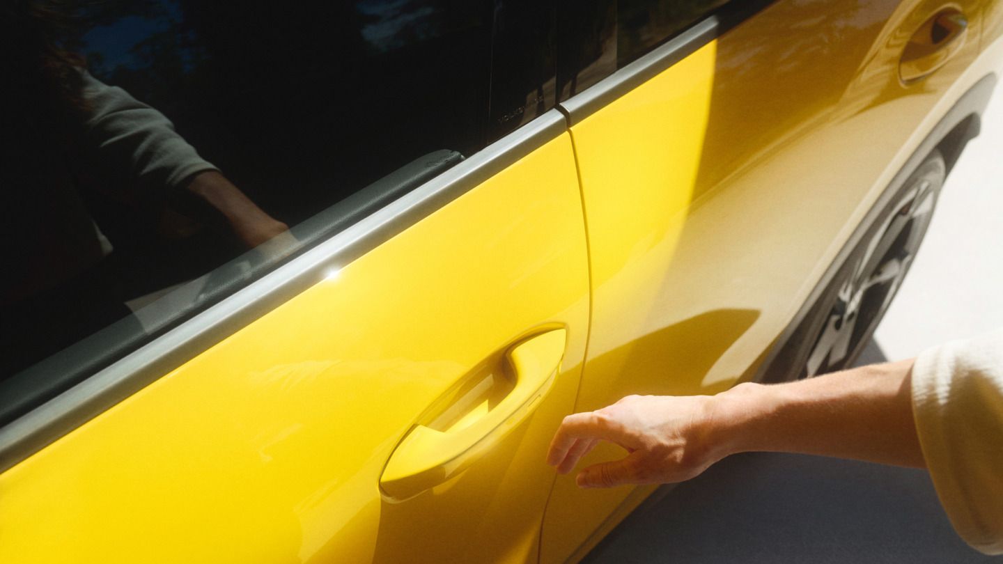 Uma mão abre o VW T-Roc R-Line amarelo com o sistema Keyless Access.