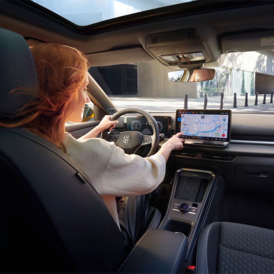 VW T-Roc Uma mulher está sentada no VW T-Roc e aponta para o ecrã de navegação.