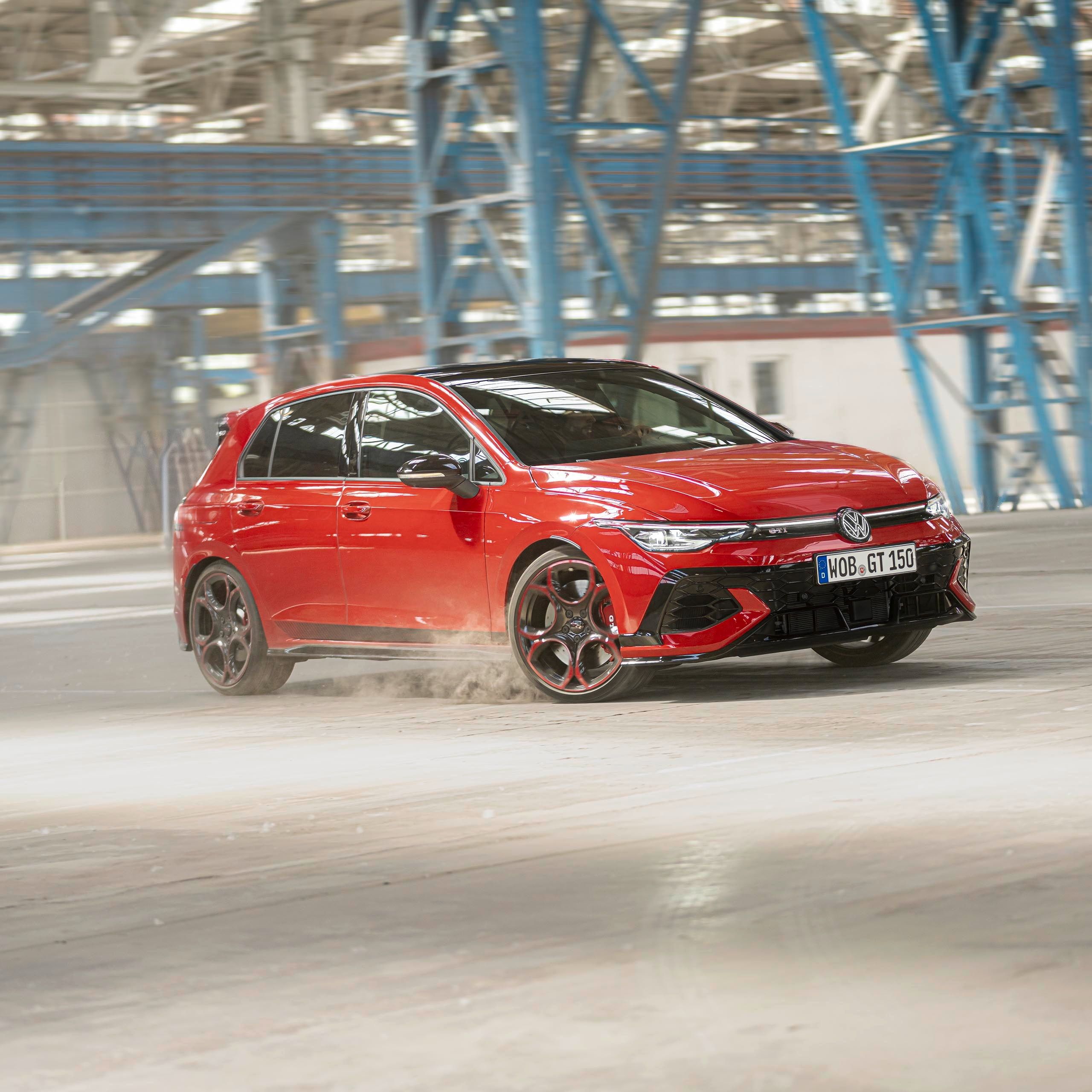 Um VW Golf GTI EDITION 50 vermelho faz uma curva num pavilhão de fábrica.