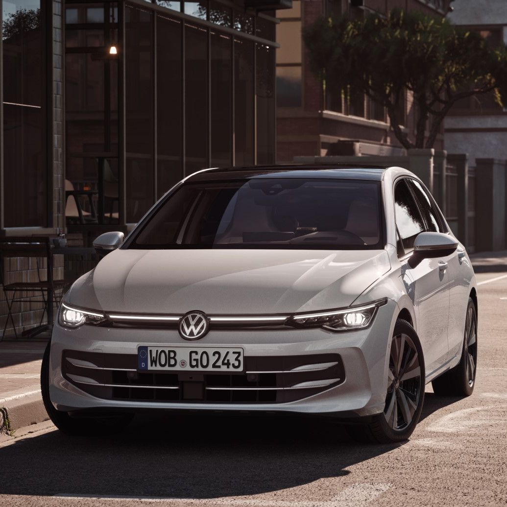 Ein weißer VW Golf von parkt seitlich vor einem Restaurant. Zwei Männer gehen in Richtung des Wagens.