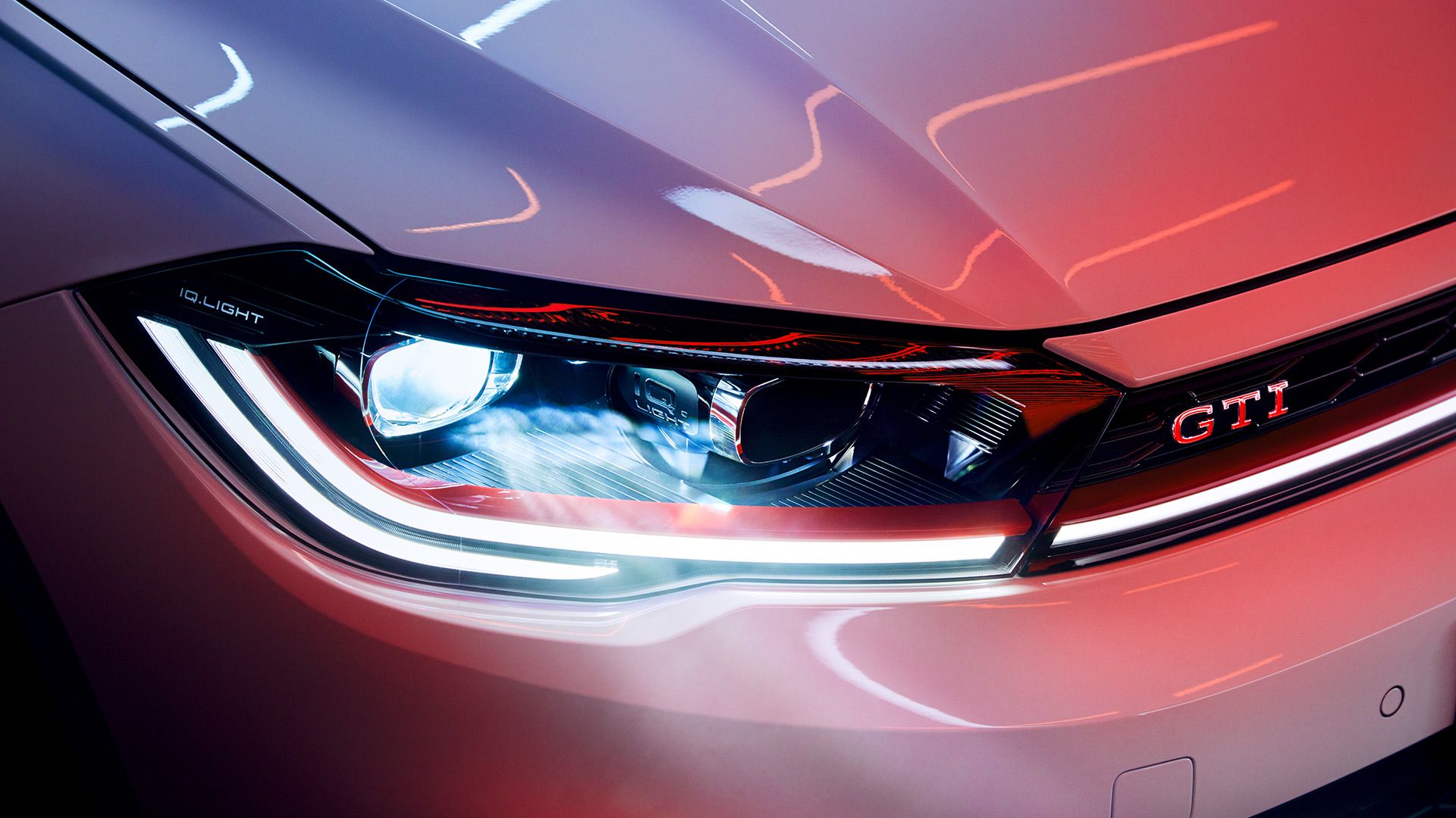 Pormenor dos faróis LED Matrix na dianteira de um VW Polo GTI branco, faixa decorativa vermelha e emblema GTI.