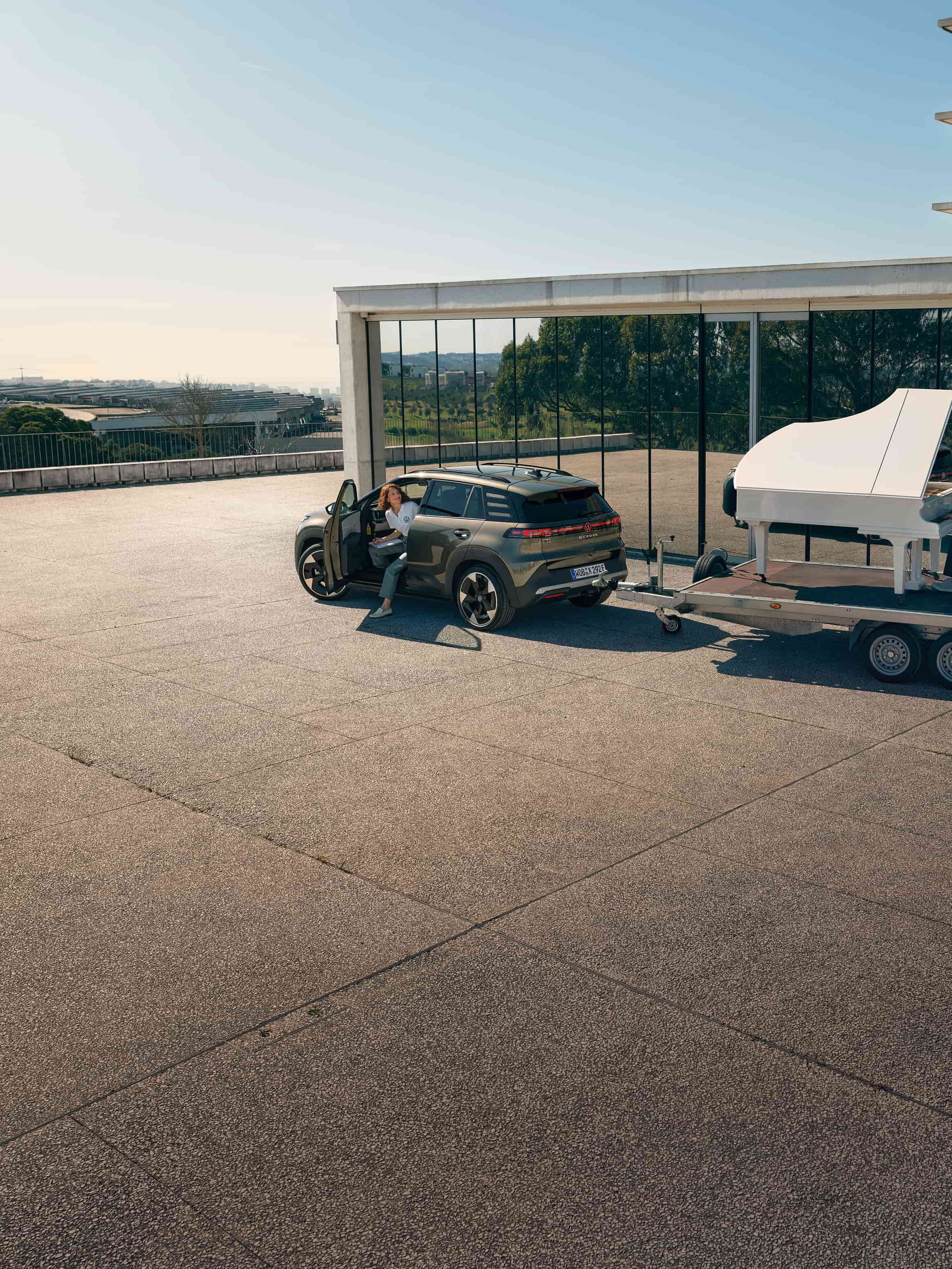 Volkswagen ID. Cross a rebocar um trailer com um homem a tocar piano.