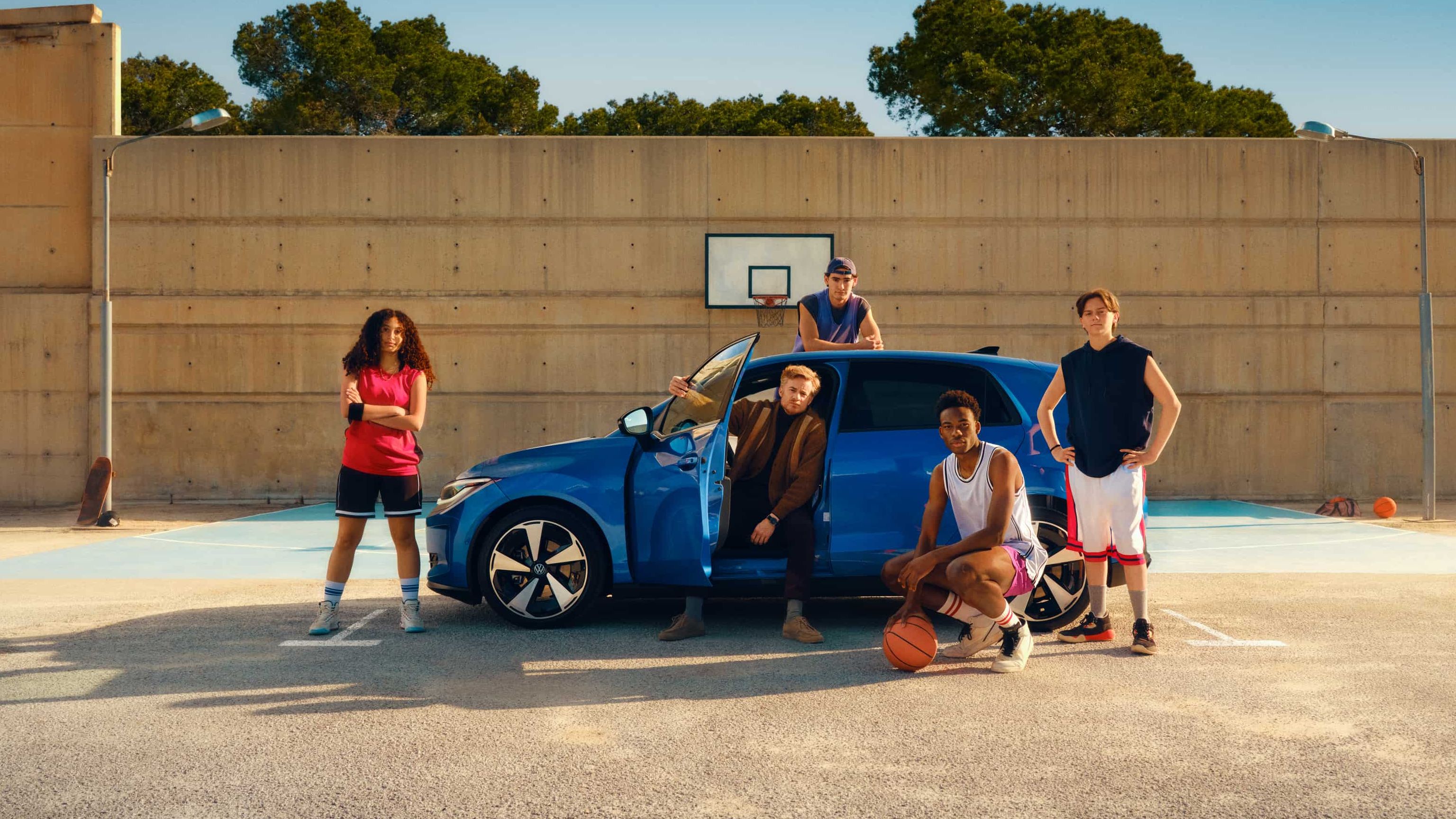 VW ID. Polo com cinco jovens, estacionado num campo de basquete ao ar livre, com a porta do condutor aberta.