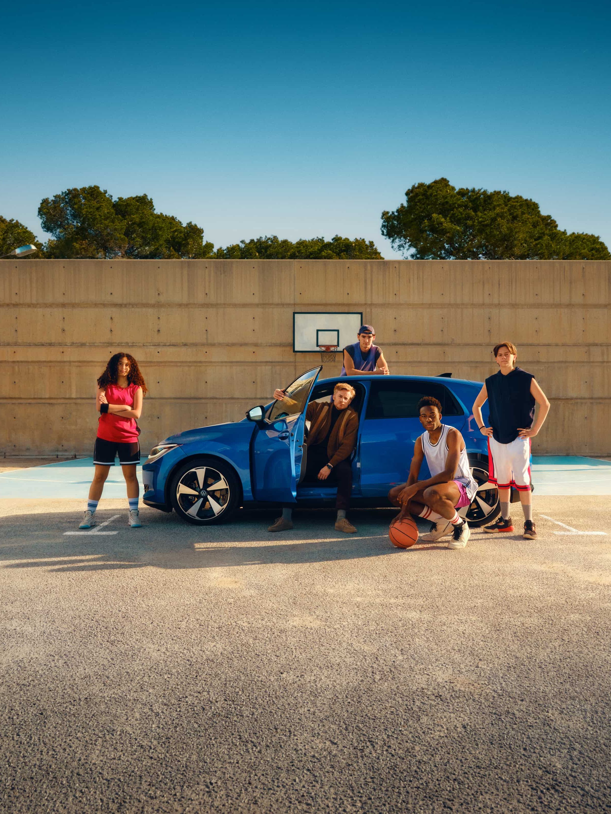 VW ID. Polo com cinco jovens, estacionado num campo de basquete ao ar livre, com a porta do condutor aberta.