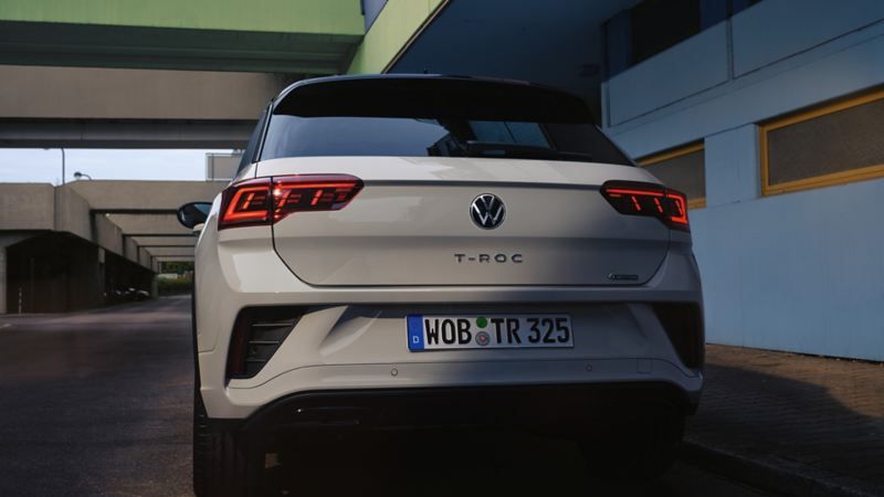 Vista de trás de um VW T-Roc branco, estacionado à beira da estrada