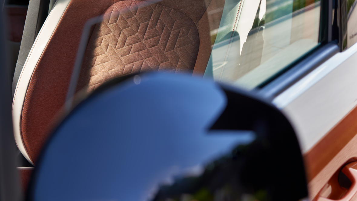 Uma rapariga e um rapaz sentados no banco de trás de um VW ID.Buzz estacionado