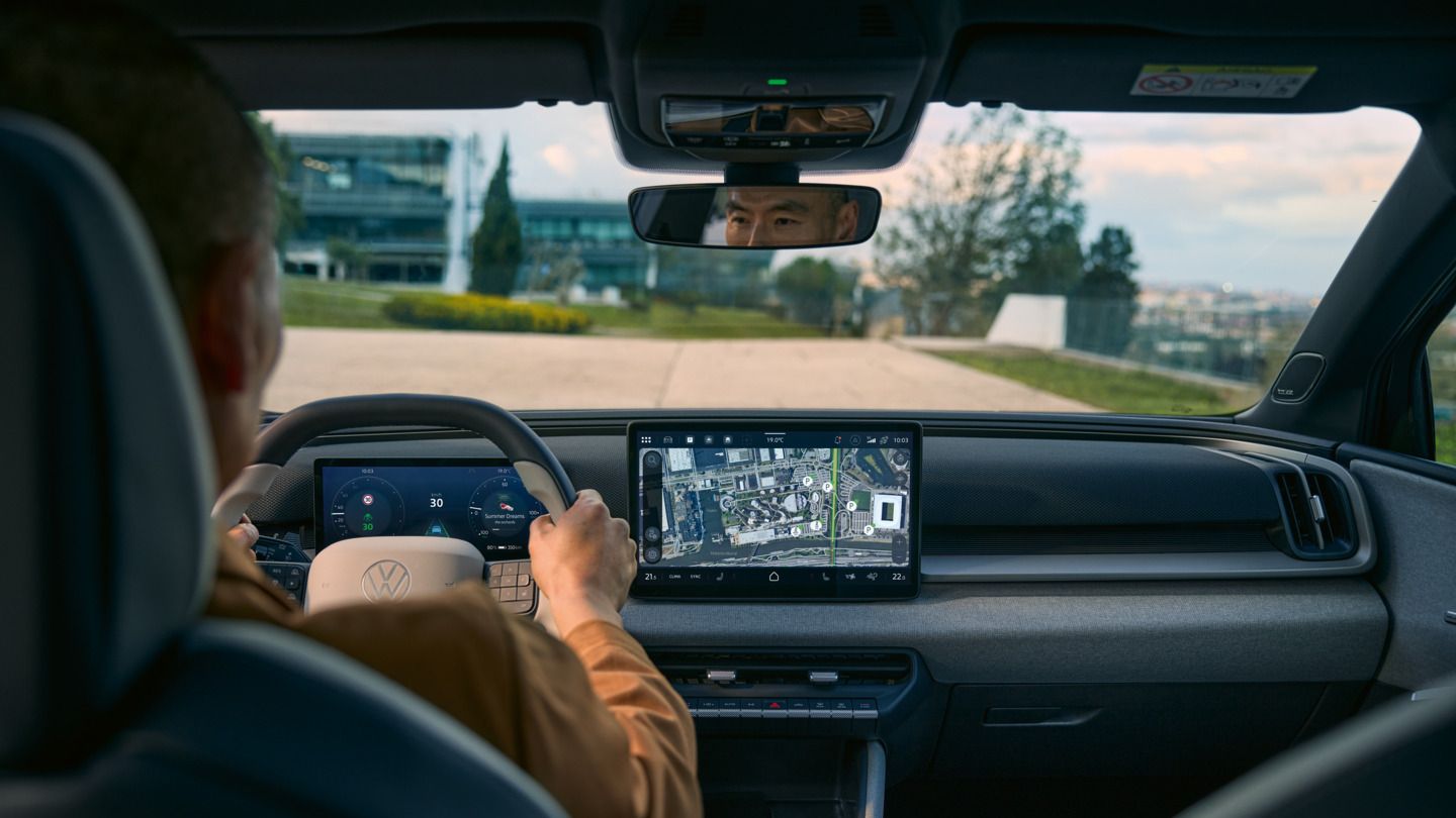 Blick vom Rücksitz in die Fahrerkabine eines VW ID. Cross mit aktiver Navigation im Infotainment-Screen.