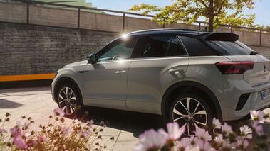 VW T-Roc em branco estacionado, vista para o lado do condutor e a traseira. 