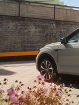 VW T-Roc em branco estacionado, vista para o lado do condutor e a traseira. 