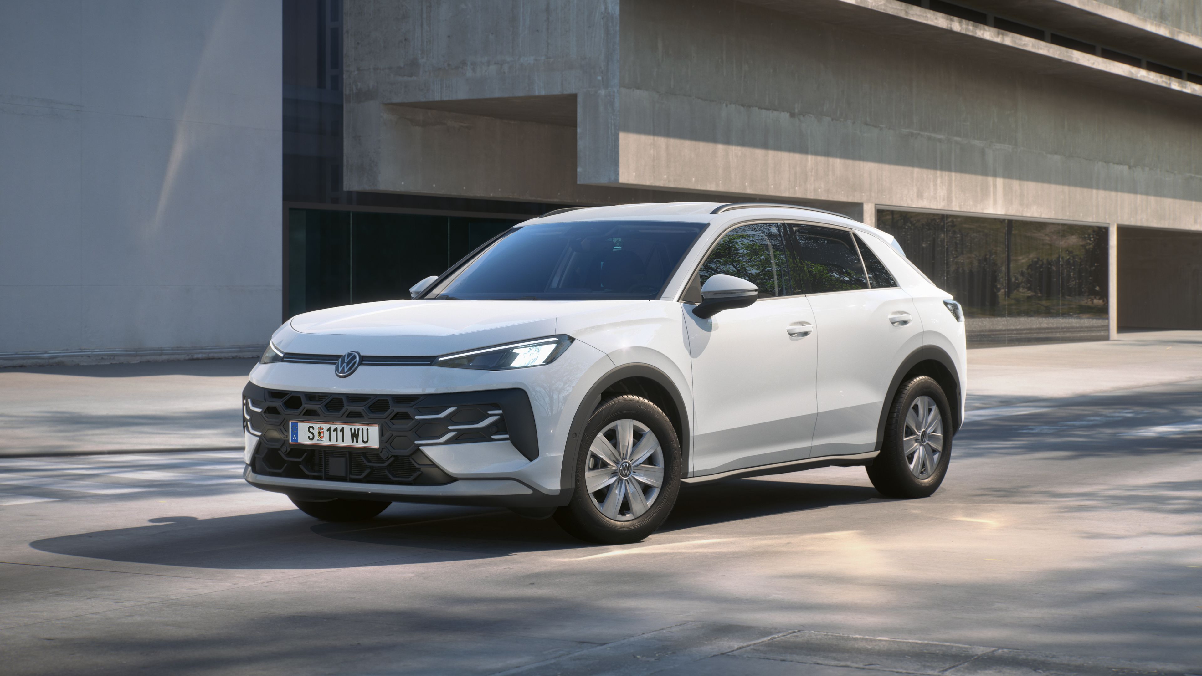 Um Volkswagen T-Roc R Trend branco está em vista frontal de 3/4 à frente de um edifício.