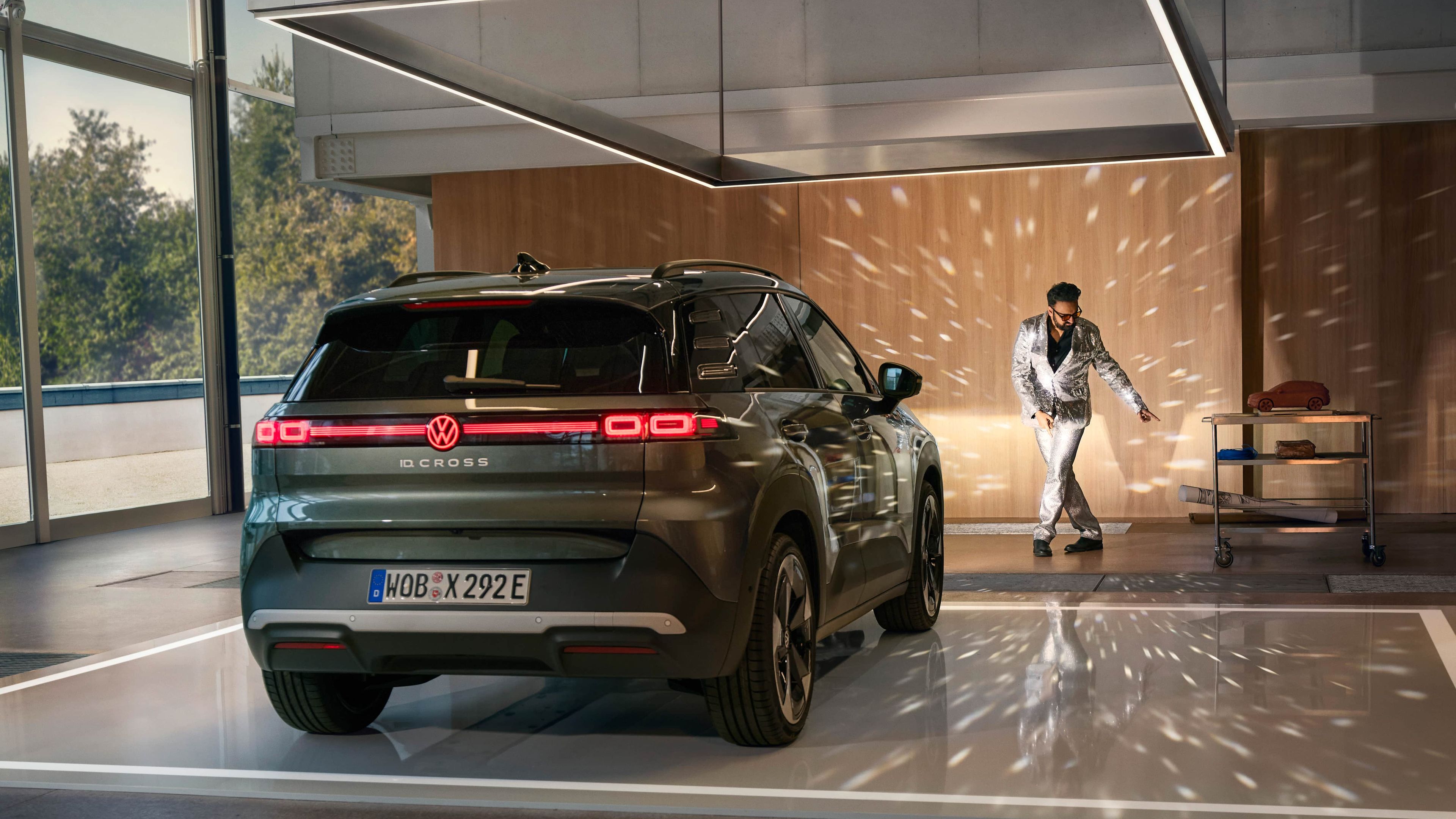 Volkswagen ID. Cross preto estacionado numa garagem moderna com reflexos de luzes tipo bola de espelho e um homem a dançar