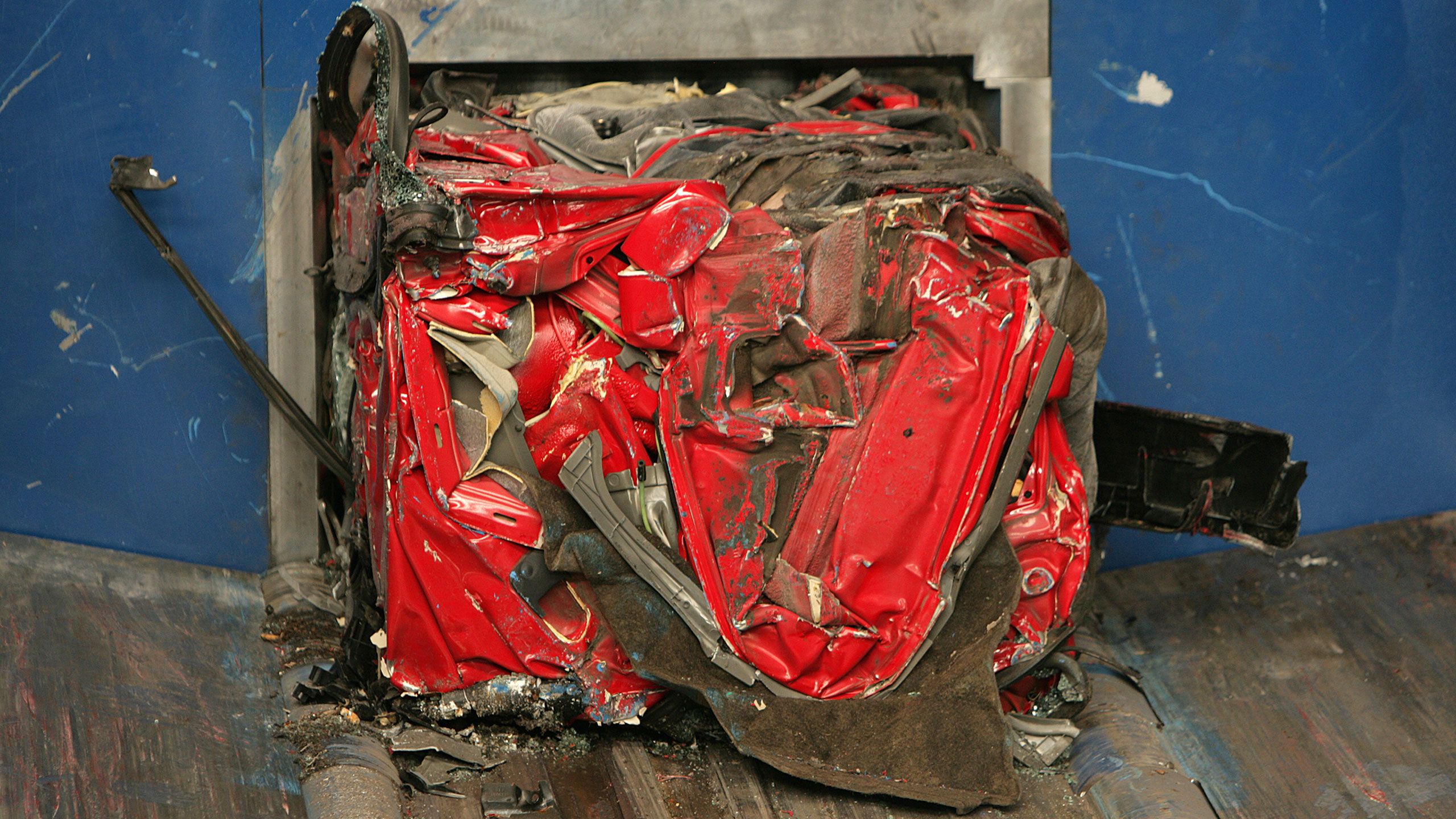 Um carro vermelho comprimido preparado para o triturador