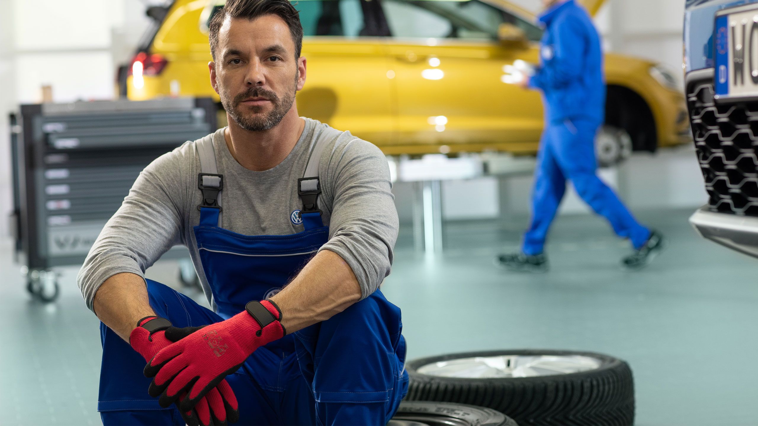 Um empregado de serviço da VW senta-se em cima de pneus empilhados de carros numa oficina