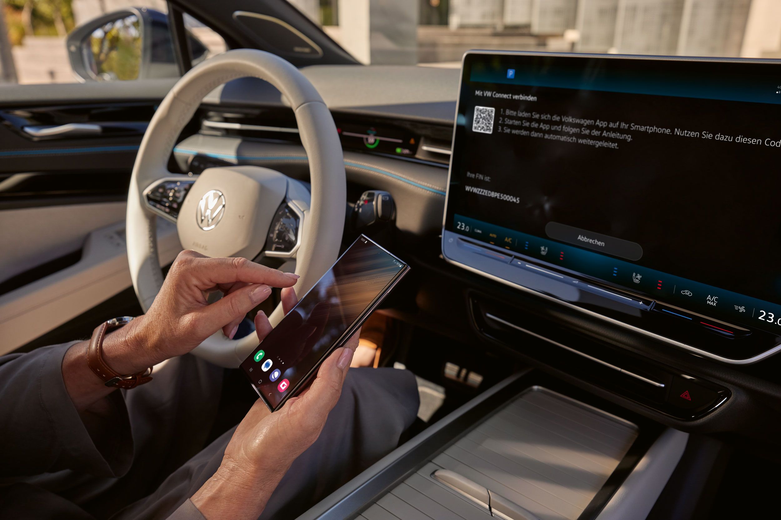 Vista sobre o cockpit no ID.7. Um smartphone está a ser ligado ao veículo via VW Connect. No visor do sistema de Infotainment vê-se a ligação ao VW Connect. 