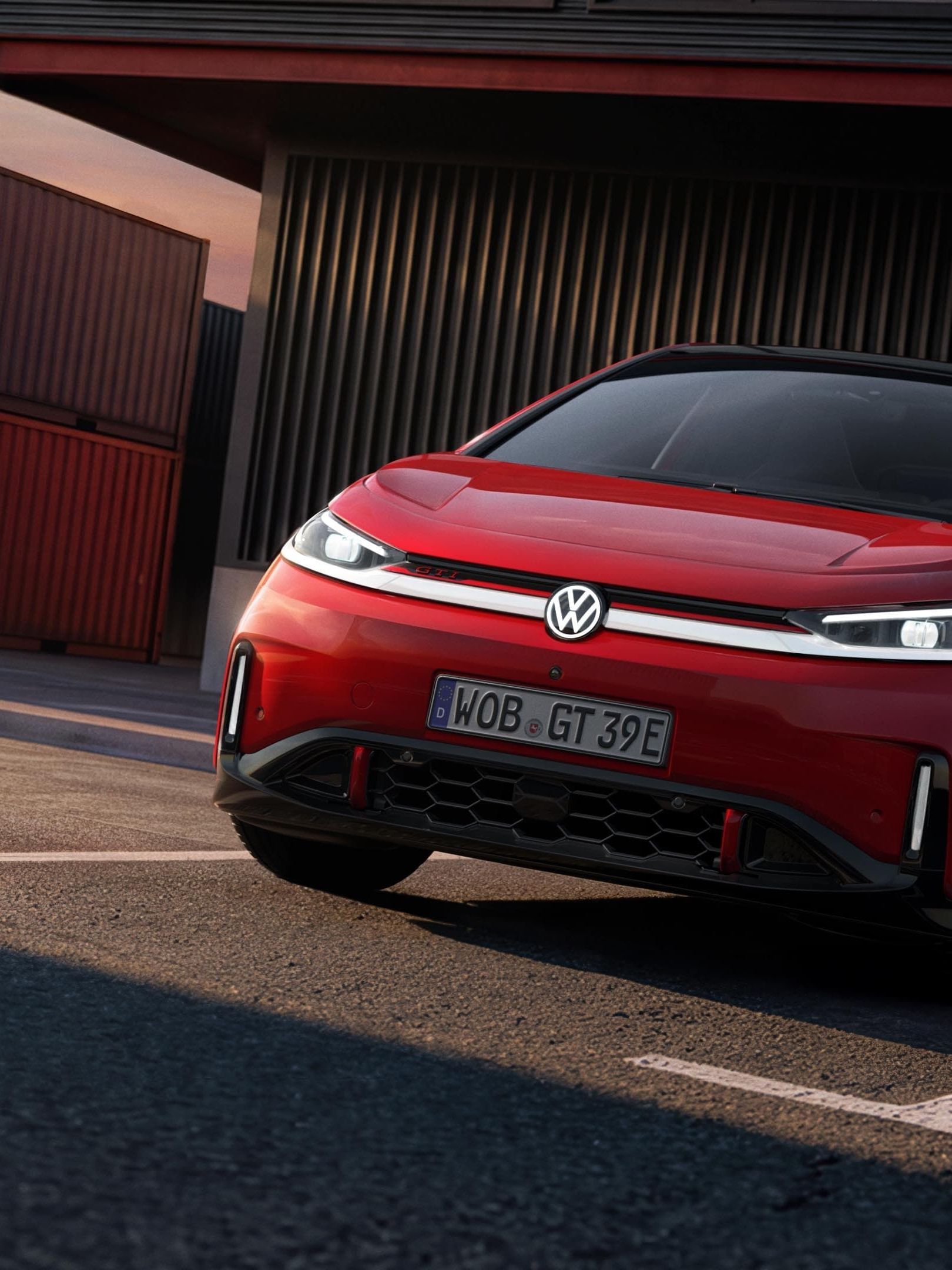 [AI-modified] – Vista frontal de um VW ID.3 GTI, com faróis e logótipo acesos, em frente a um edifício.