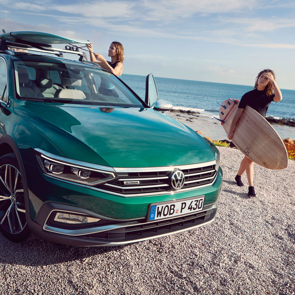 Duas mulheres vão surfar e levam as pranchas no seu automóvel VW verde