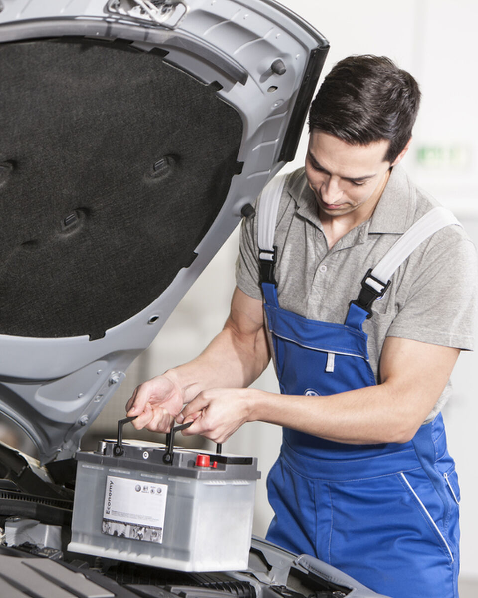 VW Batterie wird von einem Mechaniker in der VW Werkstatt ausgetauscht