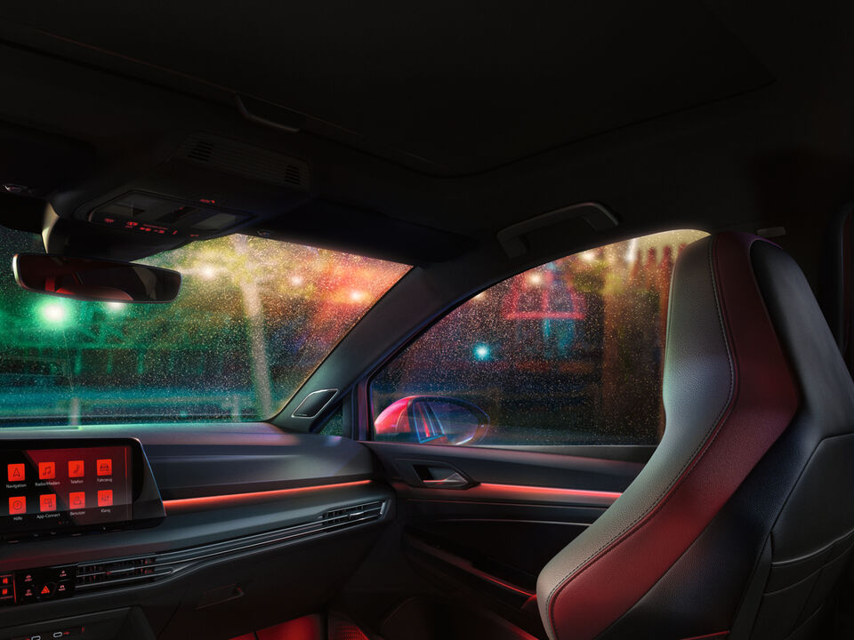 Interior do VW Golf GTI, cockpit com iluminação ambiente vermelha, com foco no banco do condutor