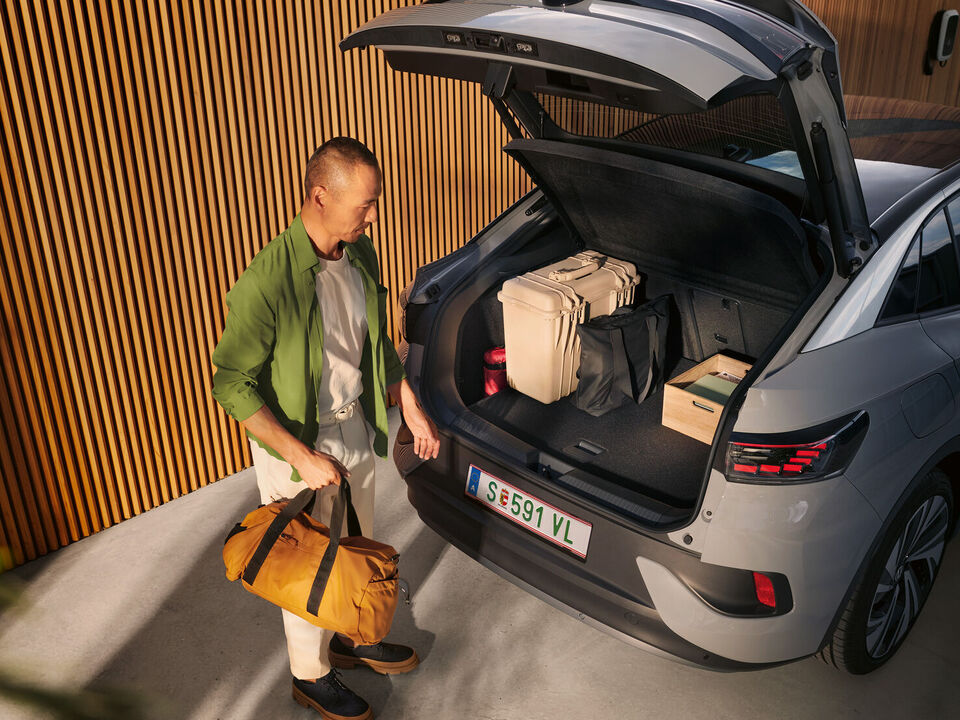 VW ID.5 com bagageira aberta e bagagem no interior, sob a tampa da bagageira aberta vê-se um homem de pasta na mão