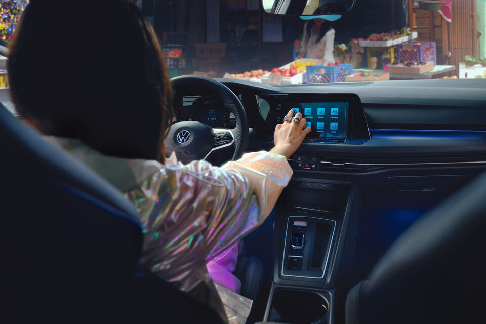 Uma mulher sentada no novo Volkswagen Golf GTE enquanto mexe no Cockpit digital.