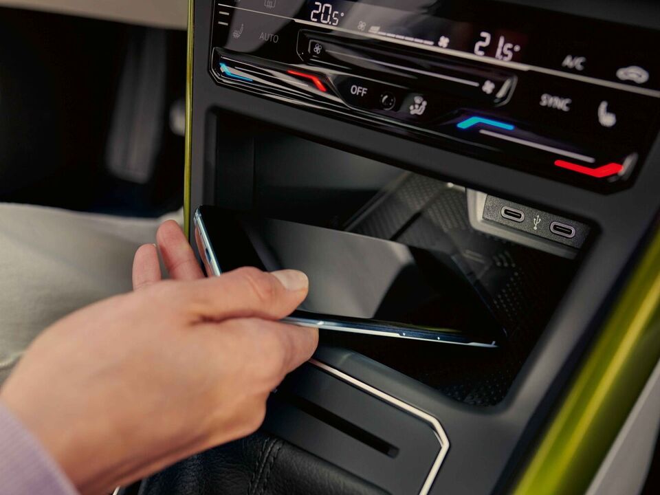 Interior do VW Taigo: Uma mulher pousa o smartphone na consola central