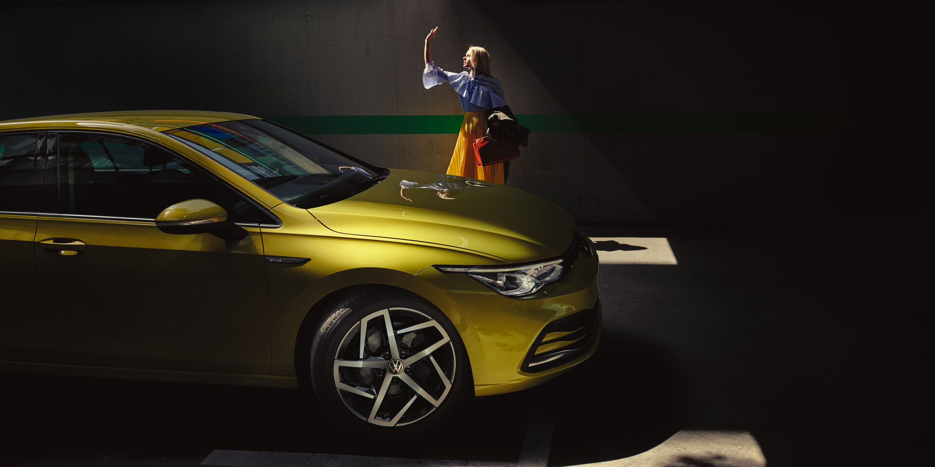 Vista lateral do VW Golf em amarelo com uma mulher sentada de lado no banco traseiro