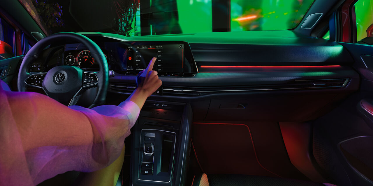 Vista detalhada do interior do VW Golf GTI com uma mulher sentada no lugar do condutor 