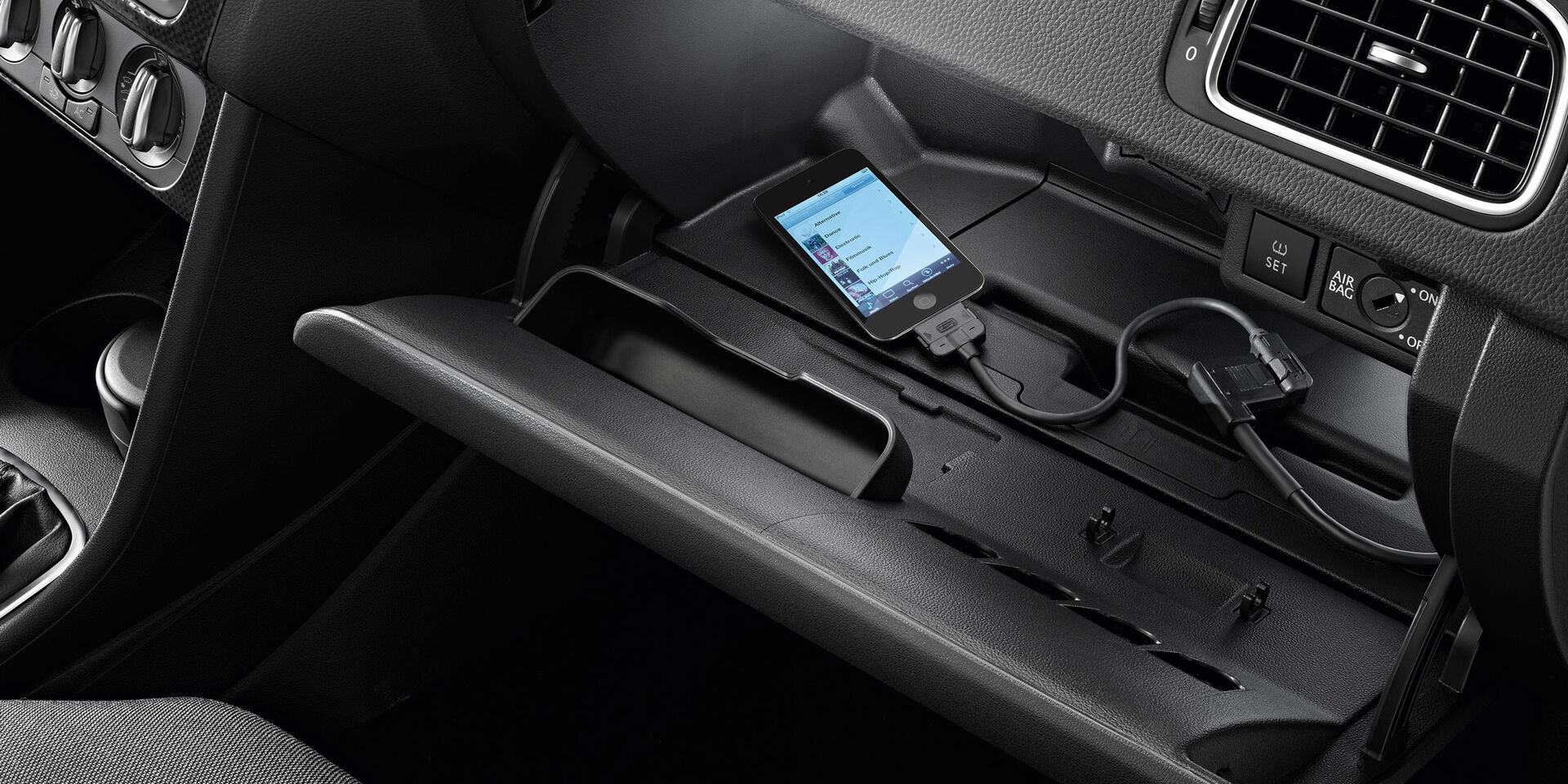 Uma vista detalhada de um smartphone a carregar dentro de um porta-luvas VW Polo 5 - Acessórios interiores Volkswagen