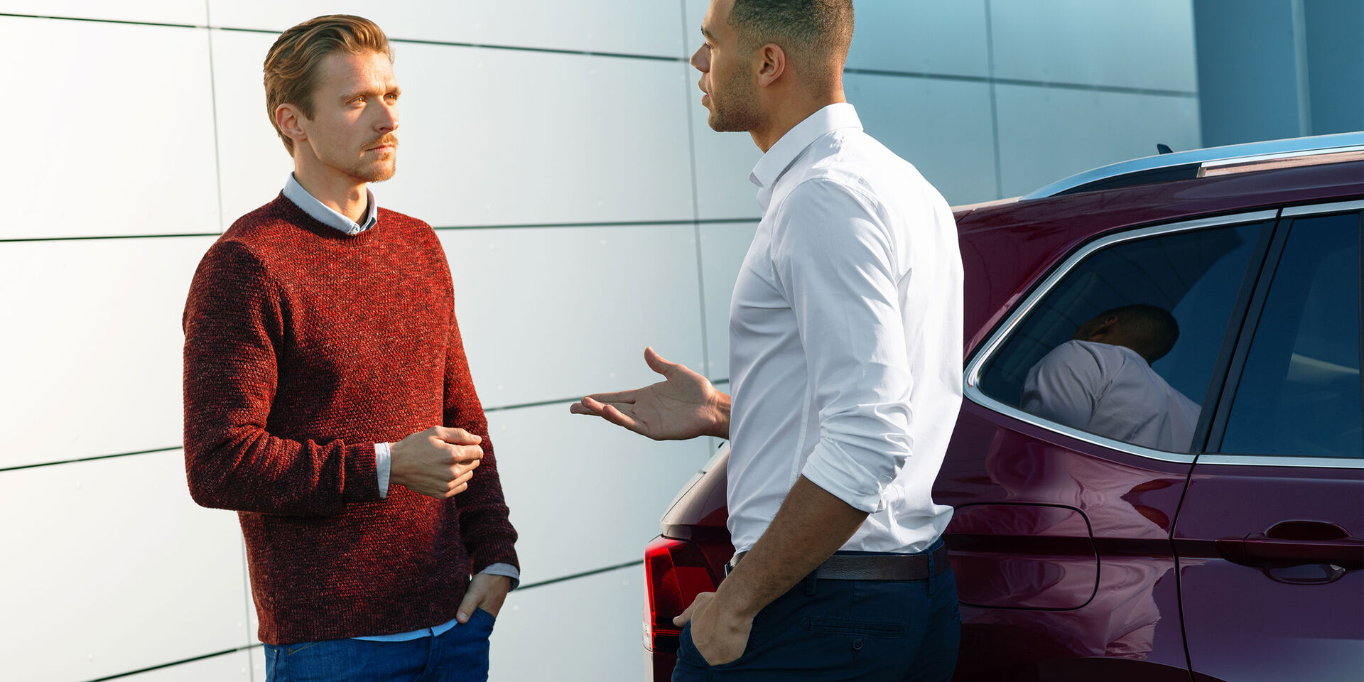 Um homem fala com um funcionário do serviço VW ao lado do seu VW vermelho