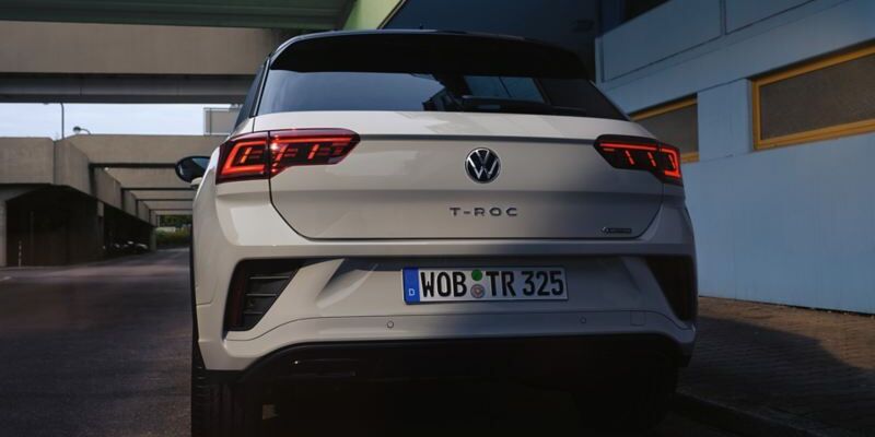 Vista de trás de um VW T-Roc branco, estacionado à beira da estrada