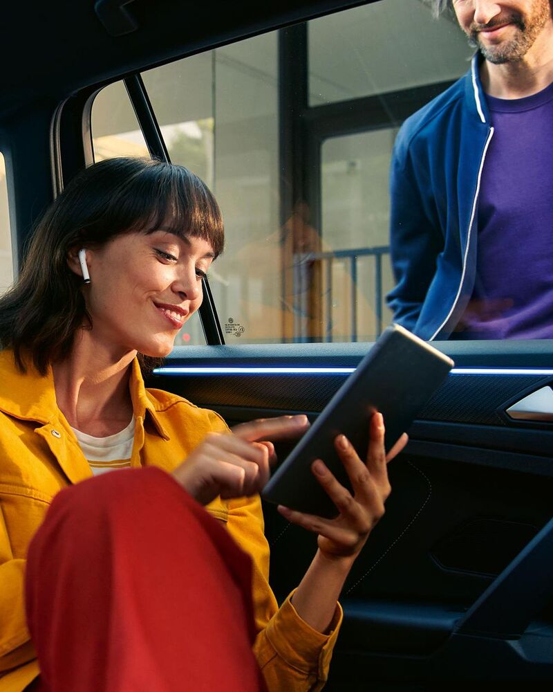 Eine Frau nutzt ein Tablet auf dem Rücksitz eines Autos