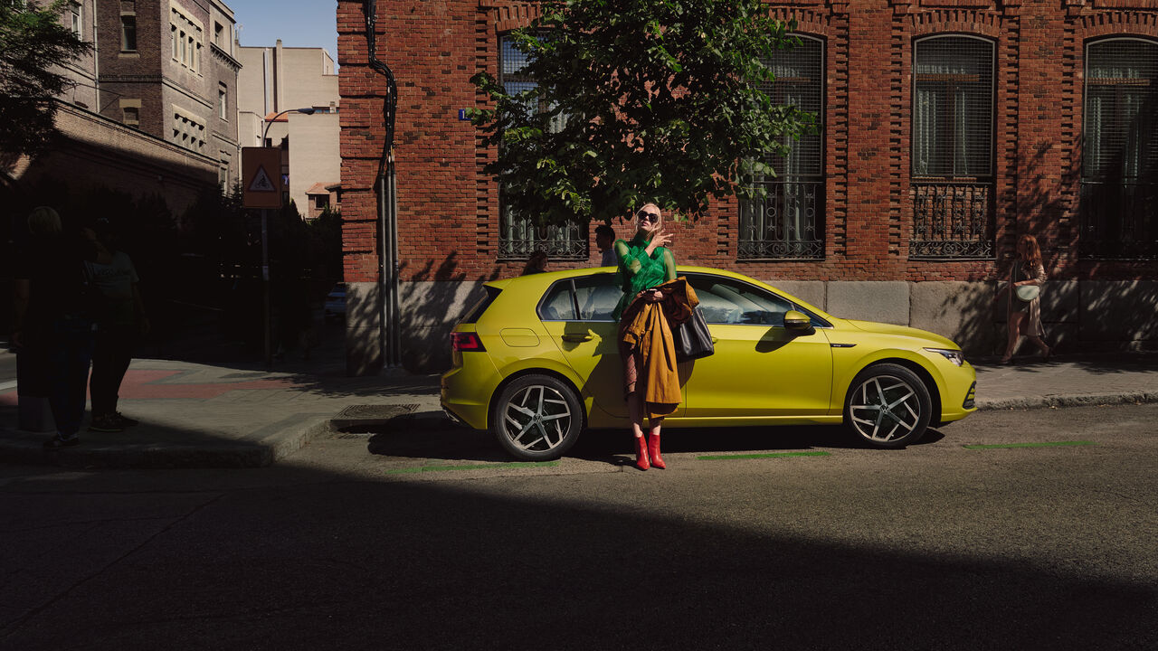 Um casal tira uma selfie junto de um VW Golf amarelo