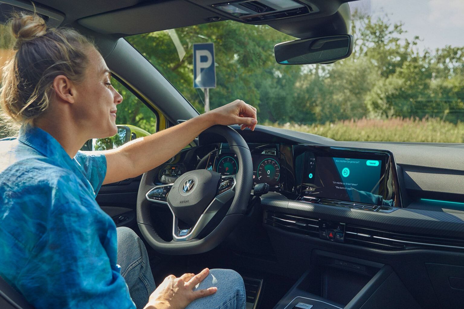 Uma mulher a usar o comando de voz no familiar VW Golf Variant