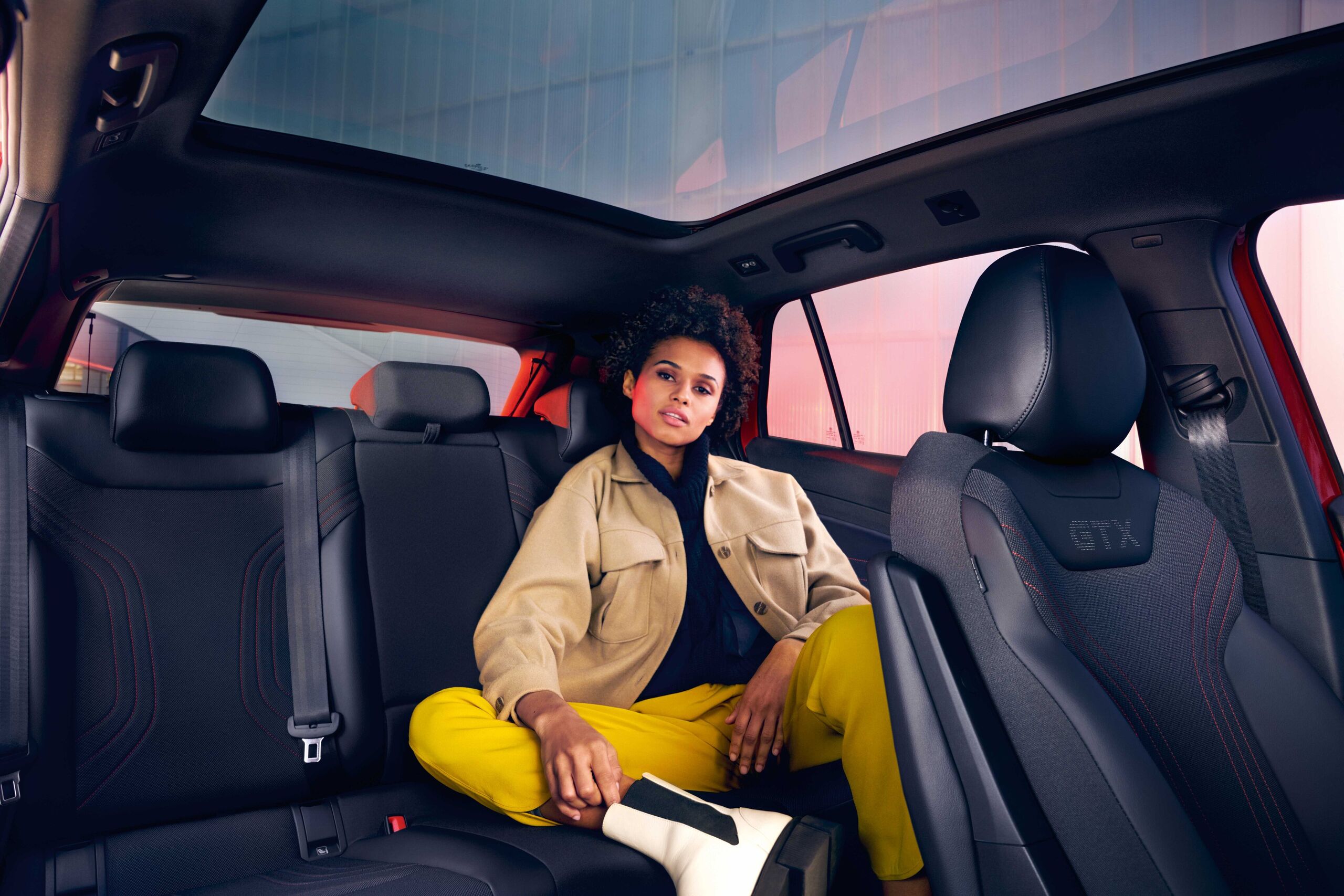 VW ID.4 GTX vista interior. Mulher sentada no banco de trás com a perna puxada para cima.
