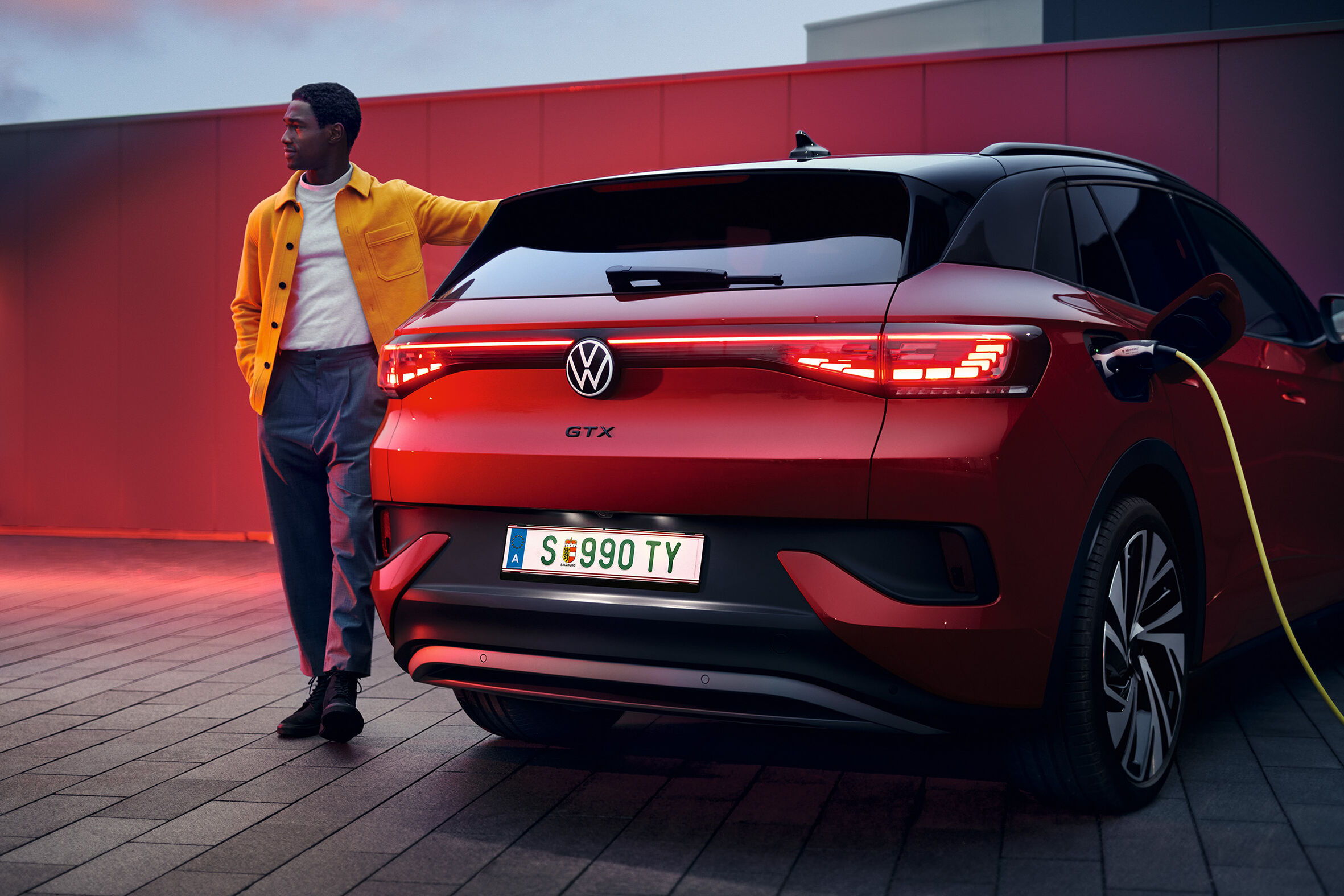 Vista traseira do VW ID.4 GTX com um jovem homem com a mão por cima do SUV elétrico desportivo.