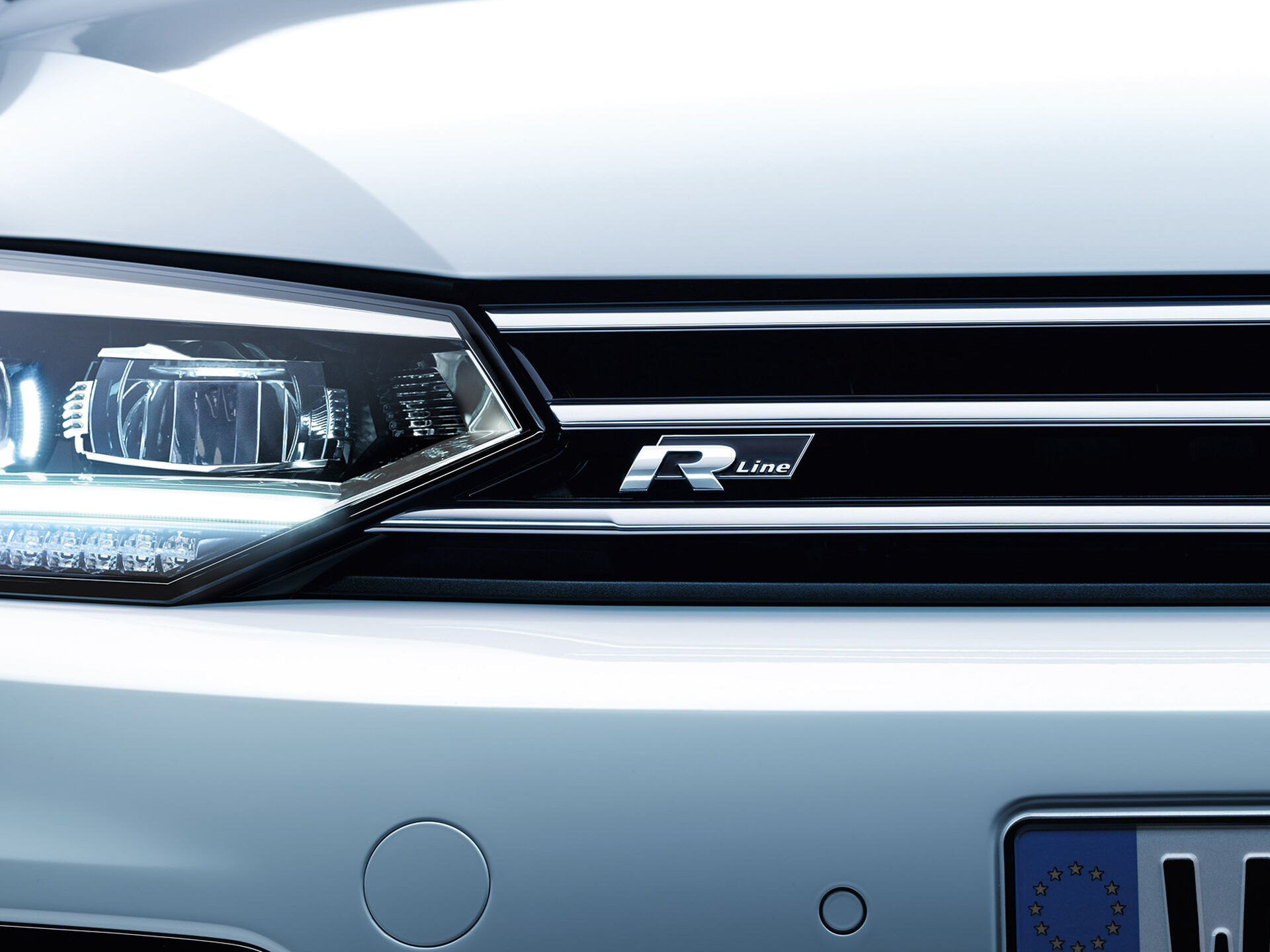 Pormenor da frente do VW Touran com faróis cortados e o logótipo "R-Line" na grelha do radiador