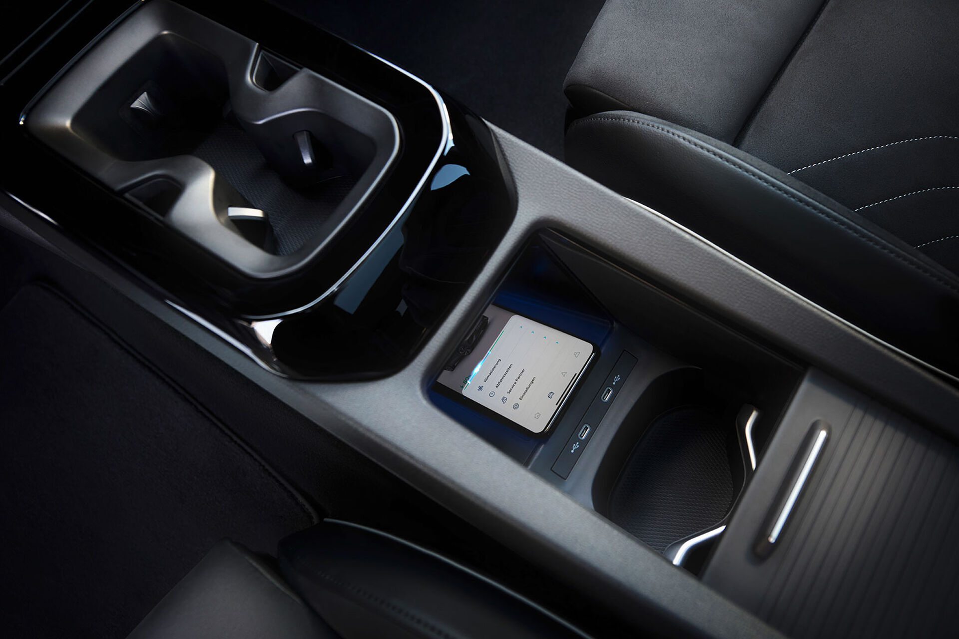 Vista da consola central com suporte de bebidas, smartphone no compartimento central, interior do VW ID.5 GTX