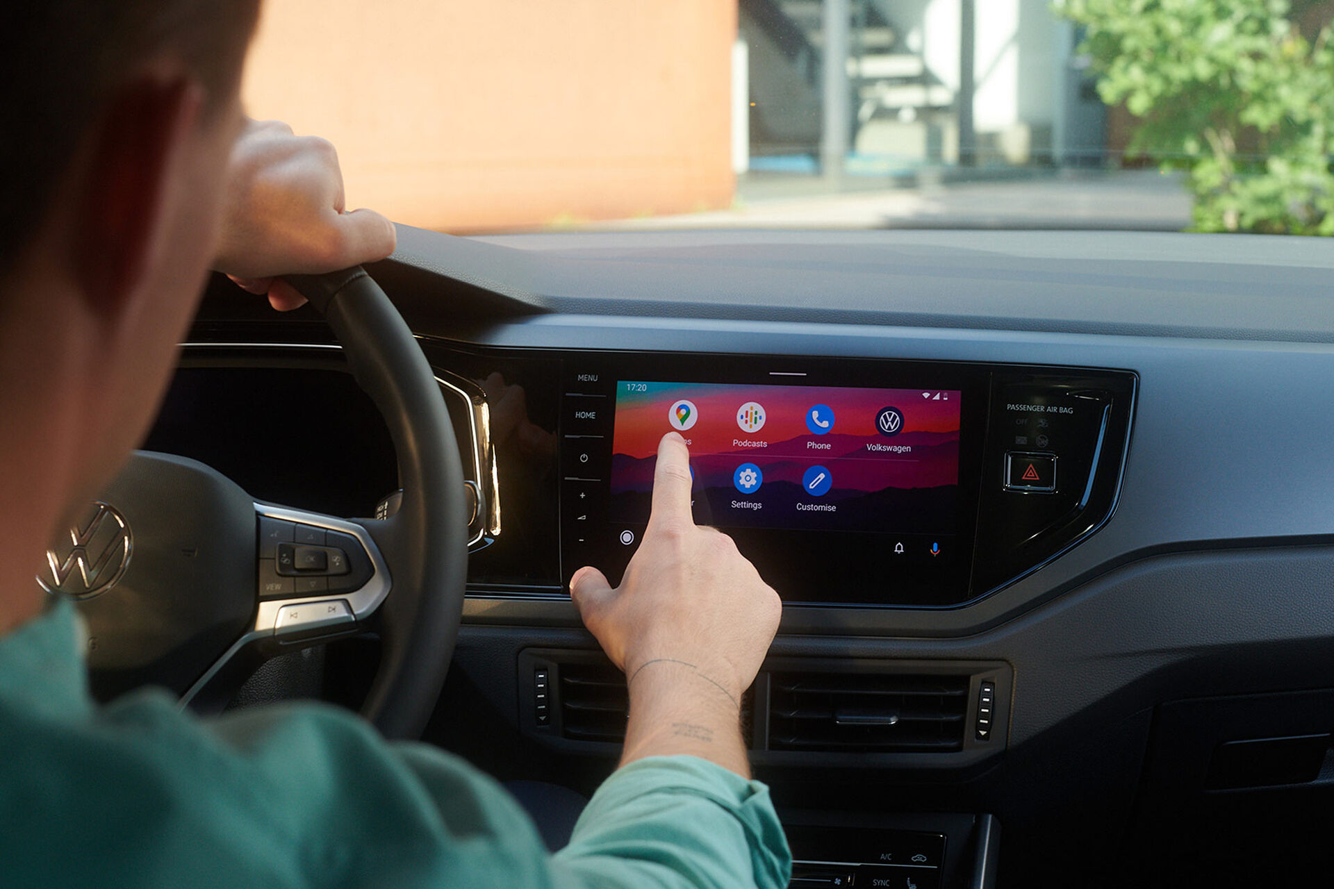 Vista do ecrã do VW Polo com funções We Upgrade. Homem sentado ao volante, a operar o ecrã. 
