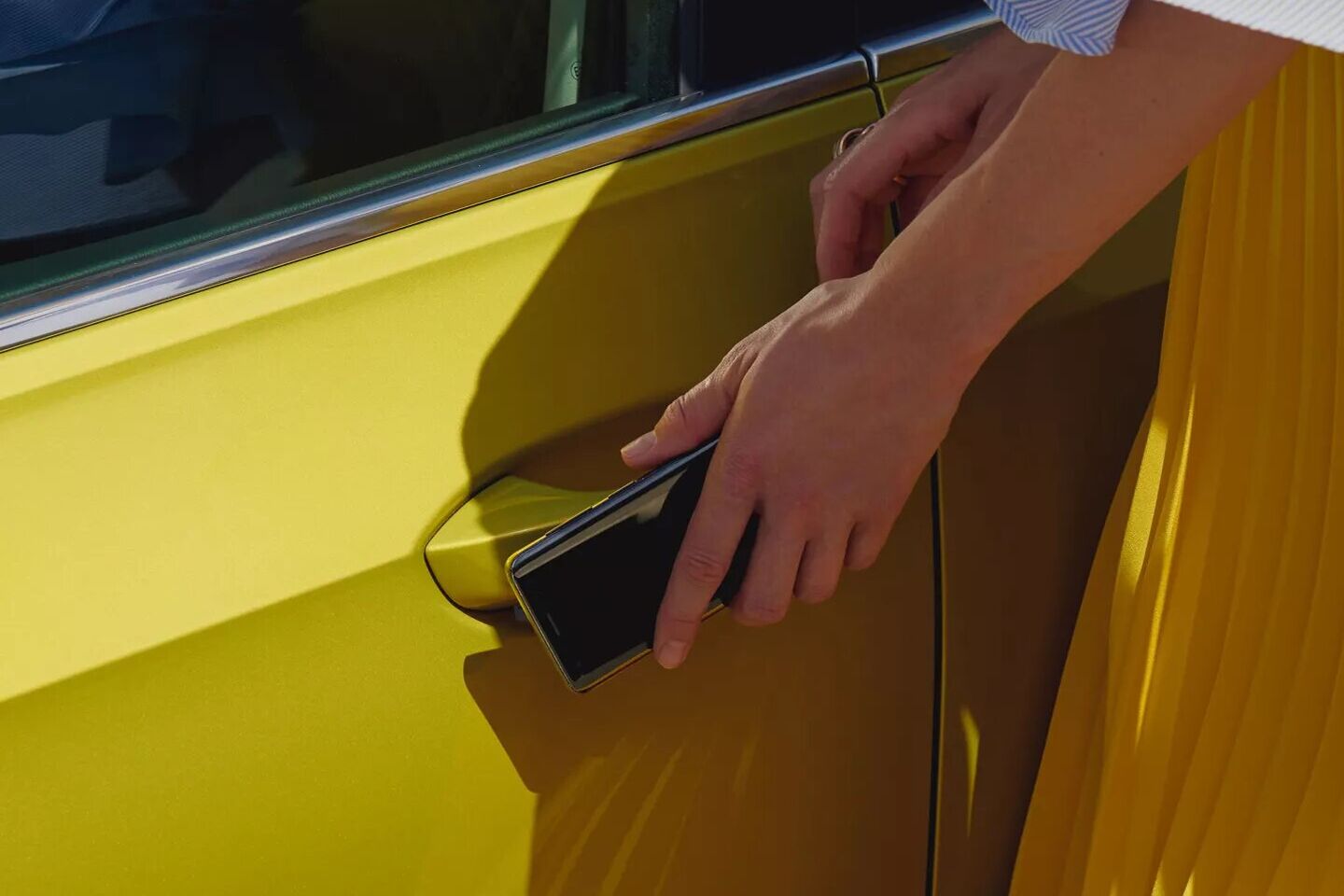 Mulher segura o telemóvel em frente ao puxador da porta do Golf